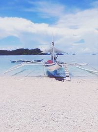 Boat moored on beach against sky