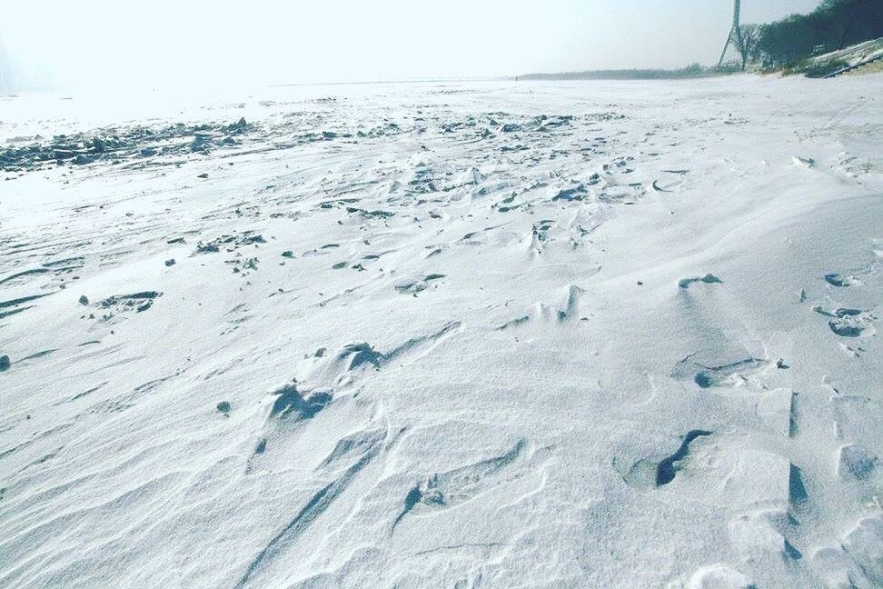 FOOTPRINTS ON SNOW COVERED LAND AGAINST SKY