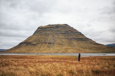 Man standing on field against cloudy sky