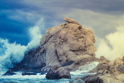 Rock formation in sea against sky