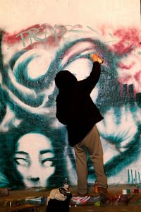Full length of man standing against graffiti in city