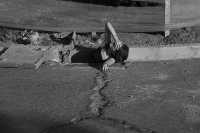 High angle view of woman covering eyes in gutter by road