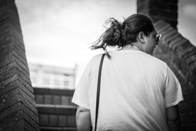 Rear view of woman standing against sky in city