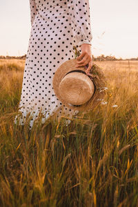 Woman holding hat on field