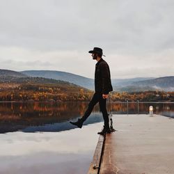 Full length of woman standing by lake against sky