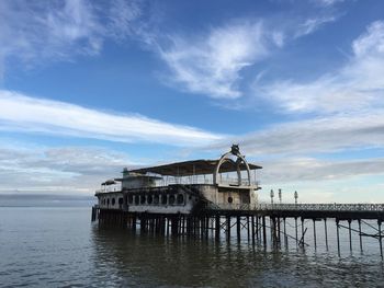 Pier on sea against cloudy sky