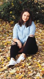 Portrait of teenage girl sitting on autumn leaves