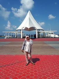 Man standing on red umbrella against sky