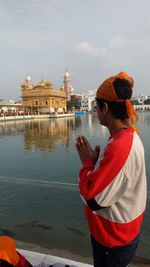 Boy praying at golden temple against sky