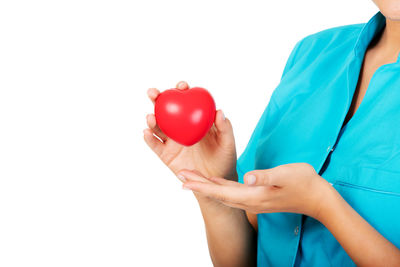 Midsection of female doctor holding heart model against white background