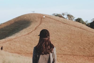 Rear view of woman standing on land against sky