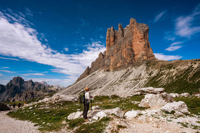 People on rock by mountain against sky