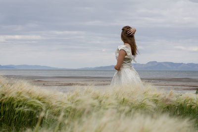 Woman standing at beach against sky