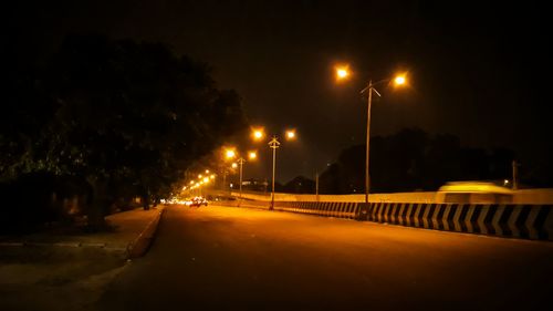 Illuminated road against sky at night