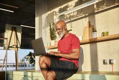 Mature man concentrating on work while using laptop at home