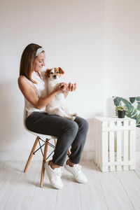 Woman with dog sitting on floor at home