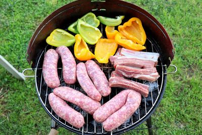 Directly above shot of sausages and vegetables being grilled on barbecue