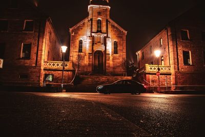 Illuminated street amidst buildings at night