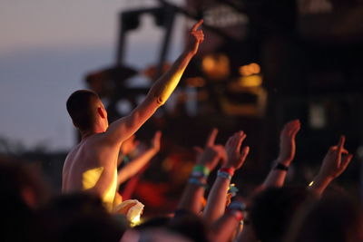 People with arms raised enjoying at music concert