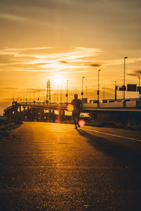 Man on street in city against sky during sunset