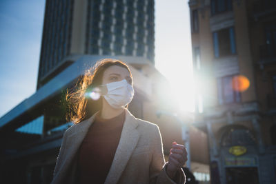 Woman wearing mask on road against buildings