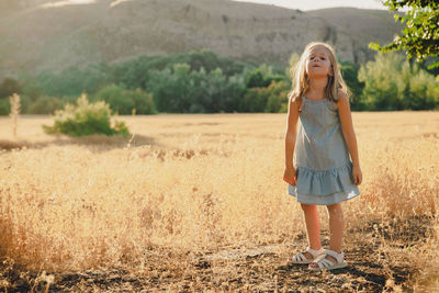 Portrait of girl standing on grassy field against mountain