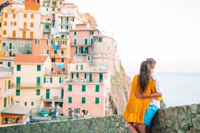 Young woman looking at buildings in city against sky