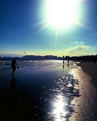 Silhouette people standing on beach against sky during sunset