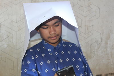 Portrait of young woman looking at camera while standing against wall