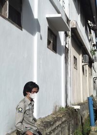 Side view of boy standing by building