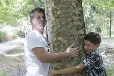 Happy friends standing against tree trunk