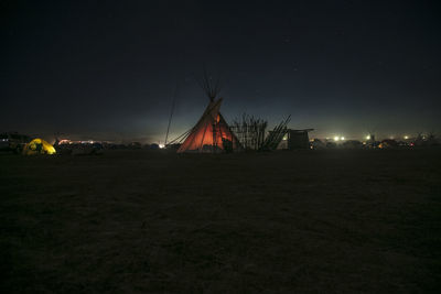 Illuminated tents on field against sky at night