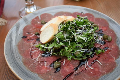 Beef carpaccio with salad, balsamic vinegar, capers, cheese and bread
