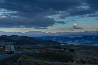 Scenic view of landscape against cloudy sky at dusk