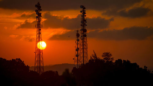 Silhouette of communications tower against sky during sunset