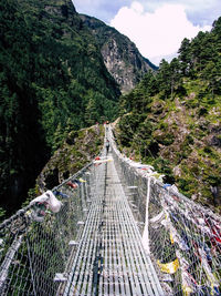 Footbridge over mountain against sky