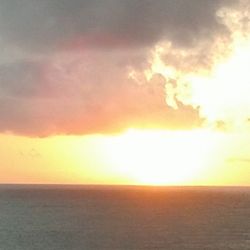 Scenic view of sea against cloudy sky at sunset