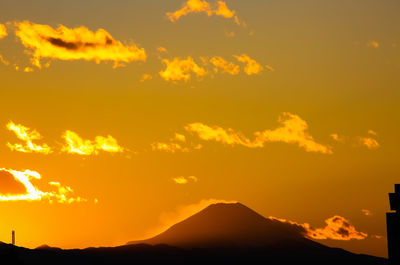 Scenic view of silhouette mountains against orange sky