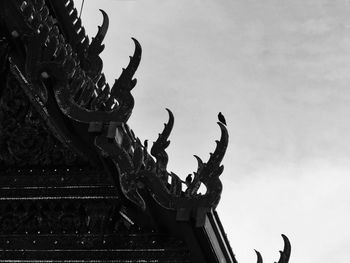 Low angle view of statue on roof against sky