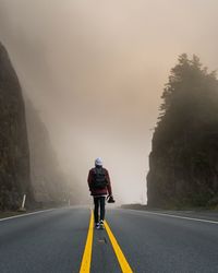 Rear view of man riding motorcycle on road