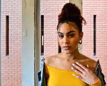 Portrait of young woman standing against wall