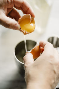 Close-up of woman breaking egg in drinking glass