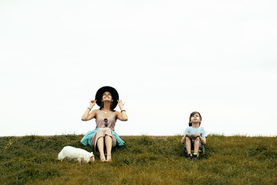 Woman sitting on field against clear sky