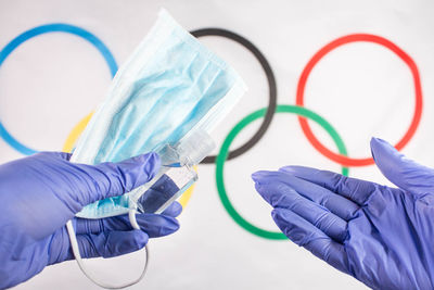 Close-up of hand holding blue paper over white background