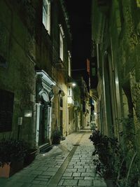 Narrow alley amidst buildings in city at night