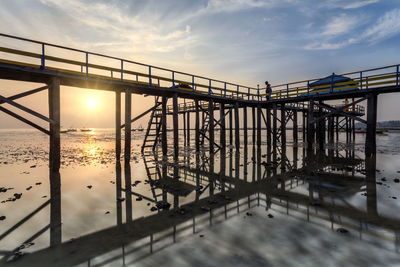 Bridge over sea against sky during sunset