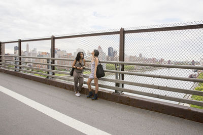 People sitting on footbridge against sky