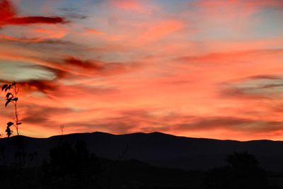 Scenic view of silhouette mountains against orange sky