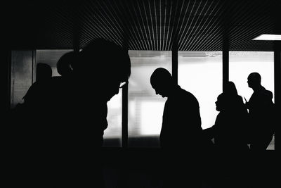 Silhouette people standing in front of window