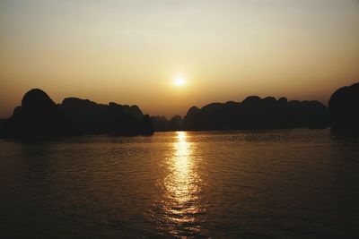 Silhouetted view of cliff by river at dusk